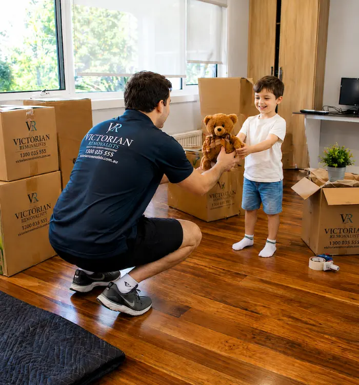 A Victorian Removalists crew member carefully handing a child their toy during a family move